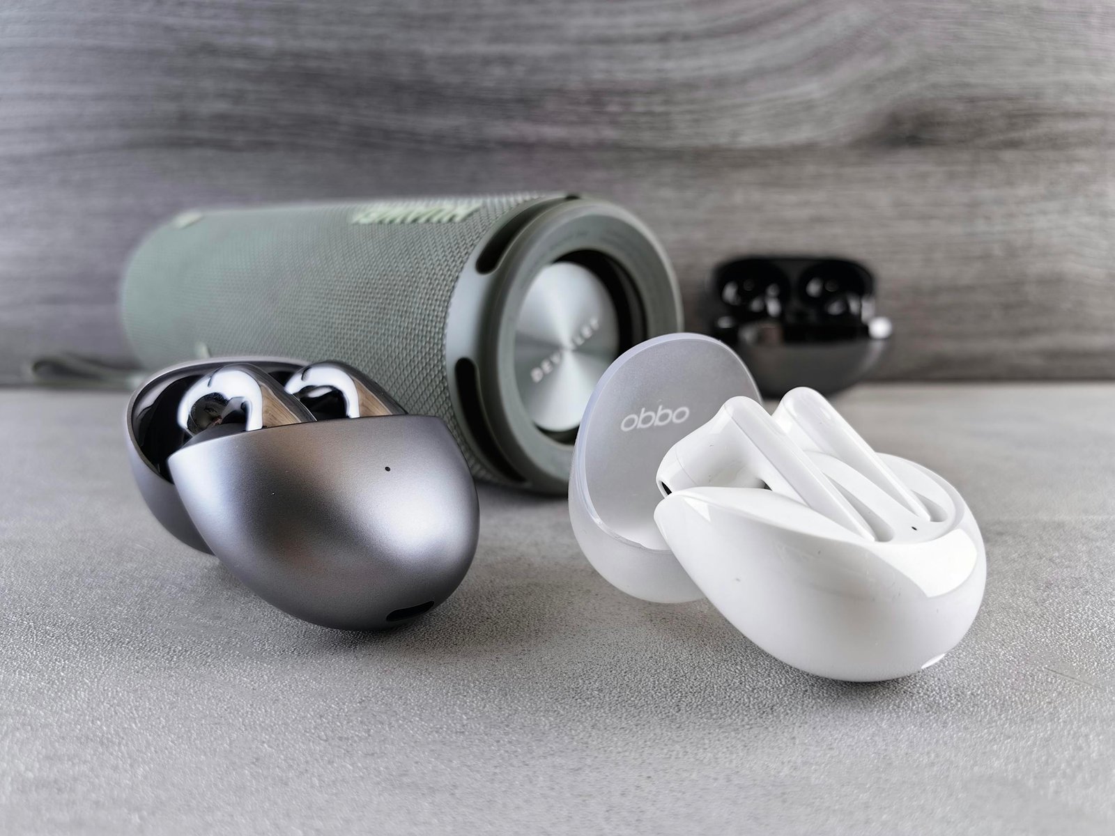 Wireless earphones and portable speaker displayed on a modern surface, showcasing sleek design and technology.